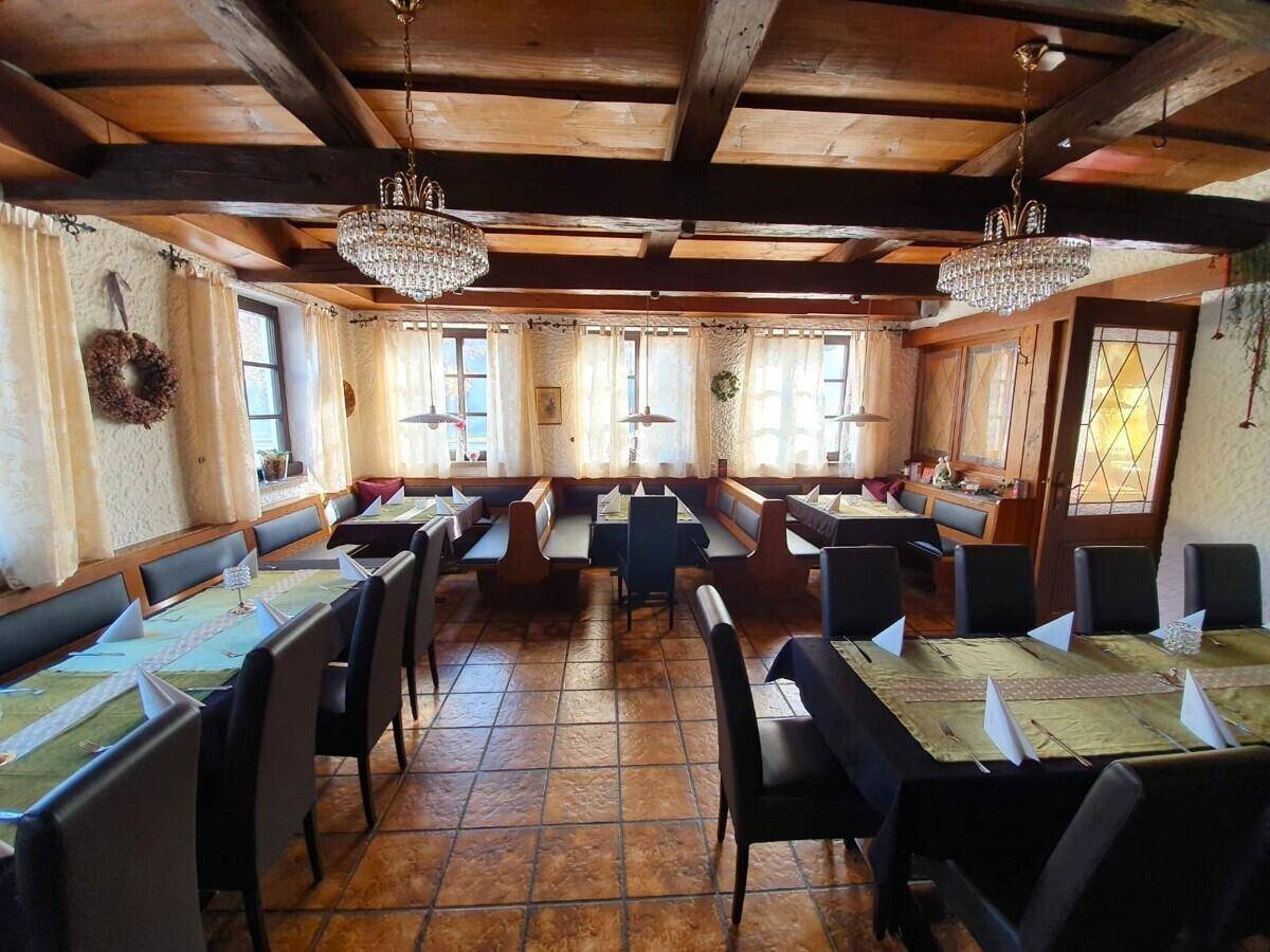 Geräumiger Speisesaal mit Holzbalkendecke, Kronleuchtern und traditionellen Sitzgelegenheiten.