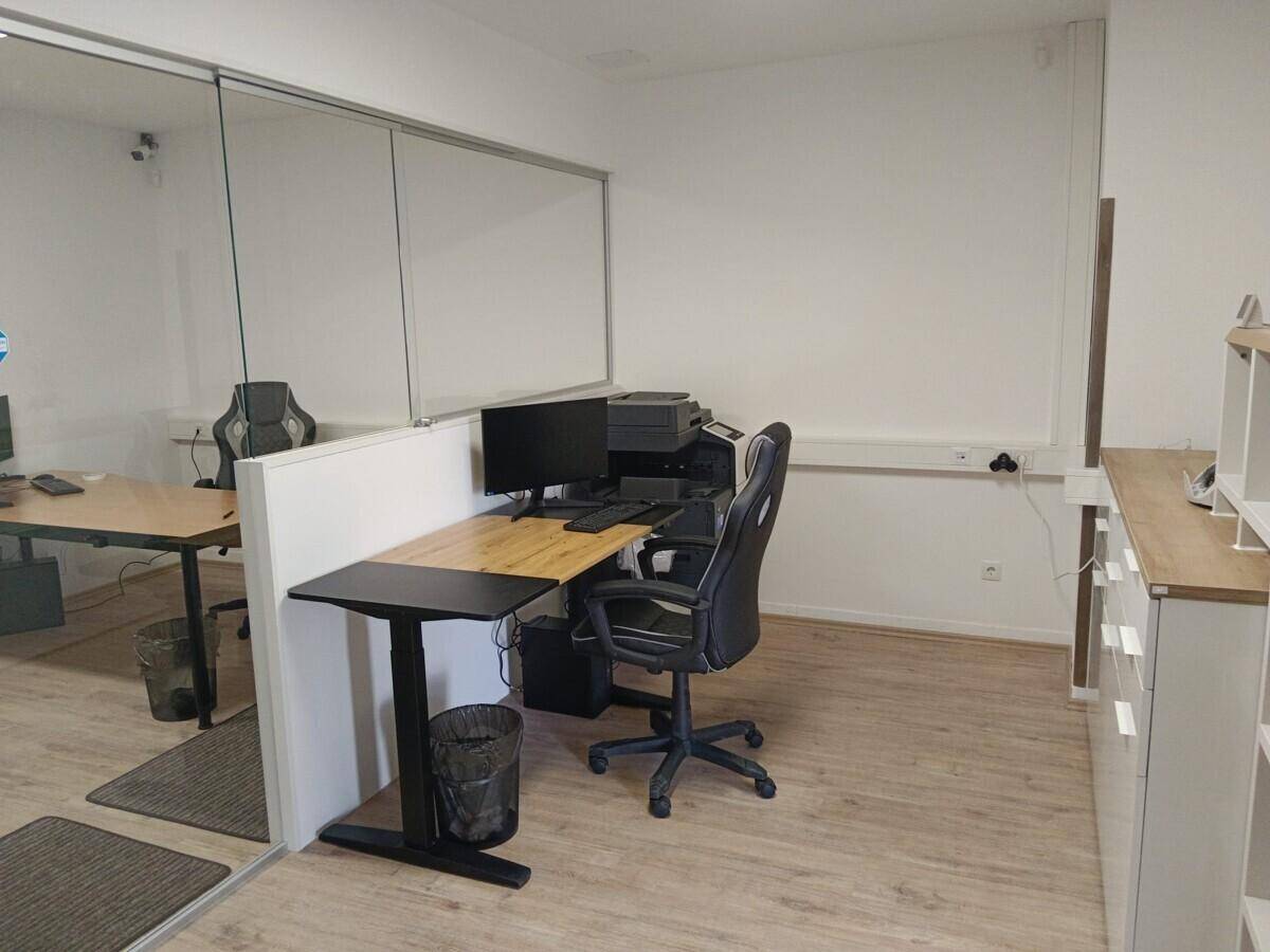 Moderner Bürobereich mit Arbeitsplatz, Stauraum und Laminatboden.