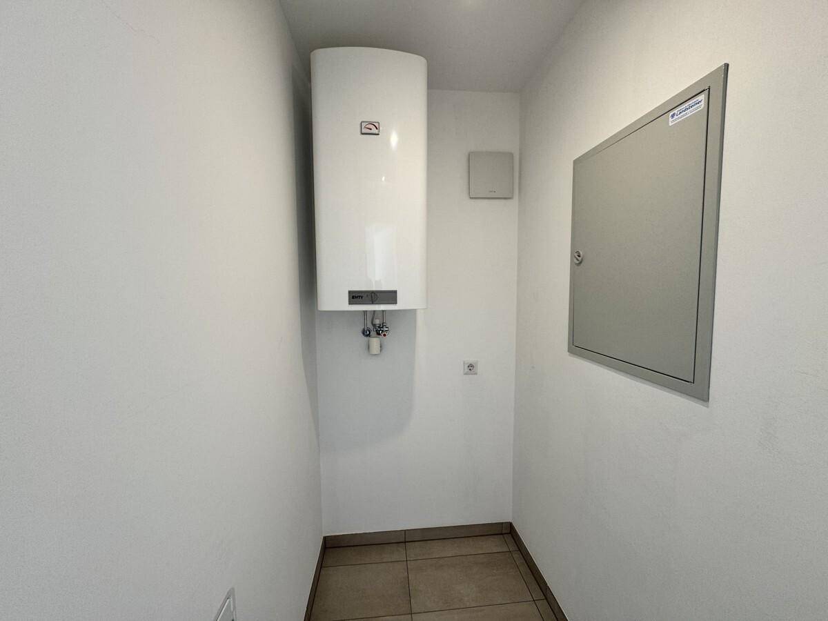 Kleiner Hauswirtschaftsraum mit Warmwasserbereiter und Elektroverteilerkasten an der Wand.