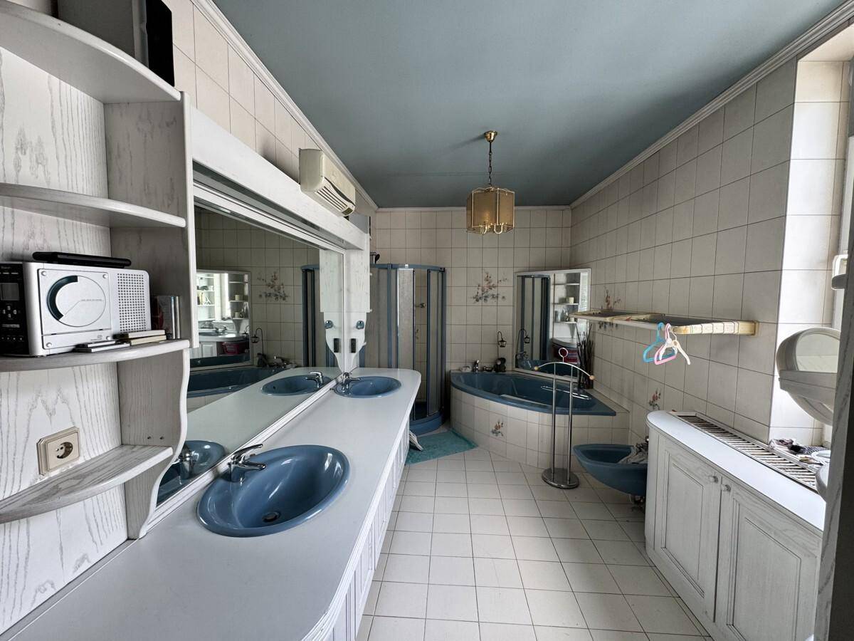 Großes Badezimmer mit Doppelwaschbecken, Eckbadewanne und blauen Akzenten.