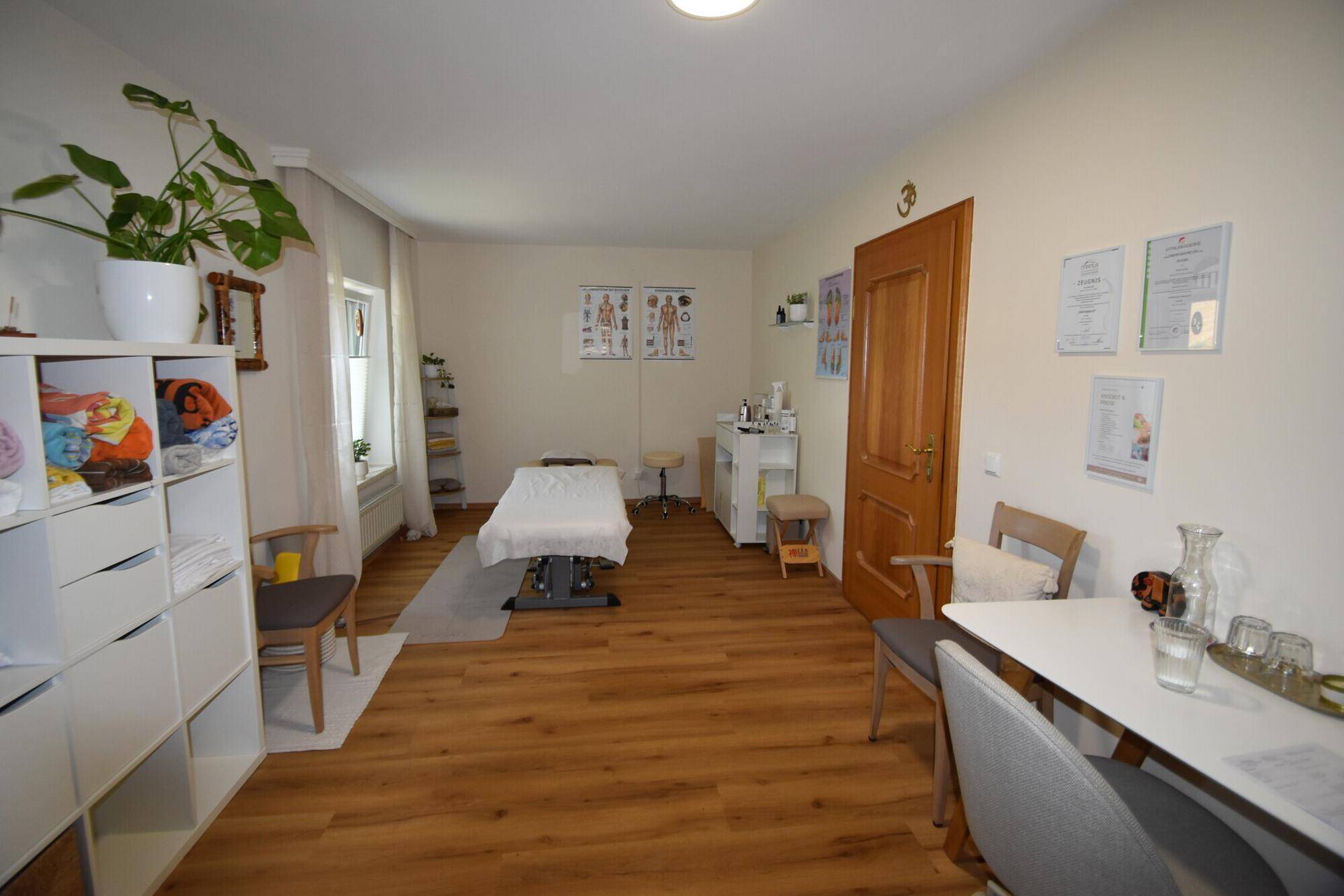 Heller Raum, eingerichtet als Behandlungs- oder Therapiezimmer mit Holzboden.