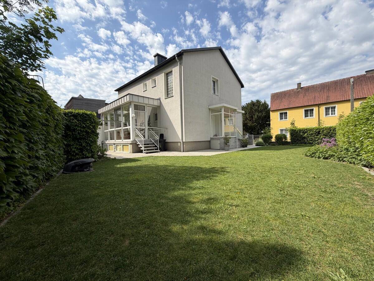 Weitläufiger Gartenbereich hinter dem Haus mit viel Grünfläche und Heckenbegrenzung.