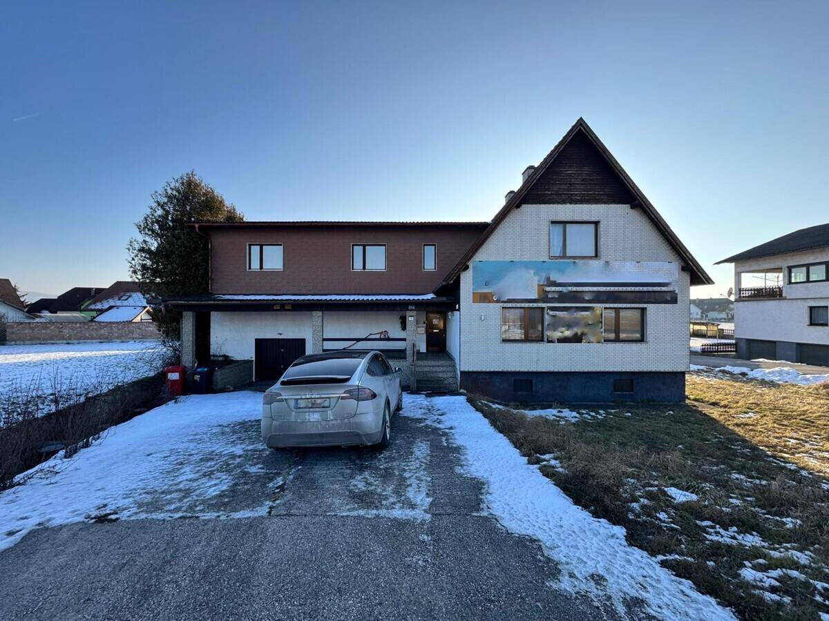 Vorderansicht des Hauses mit Garage, Einfahrt und einem geparkten Auto im Winter.