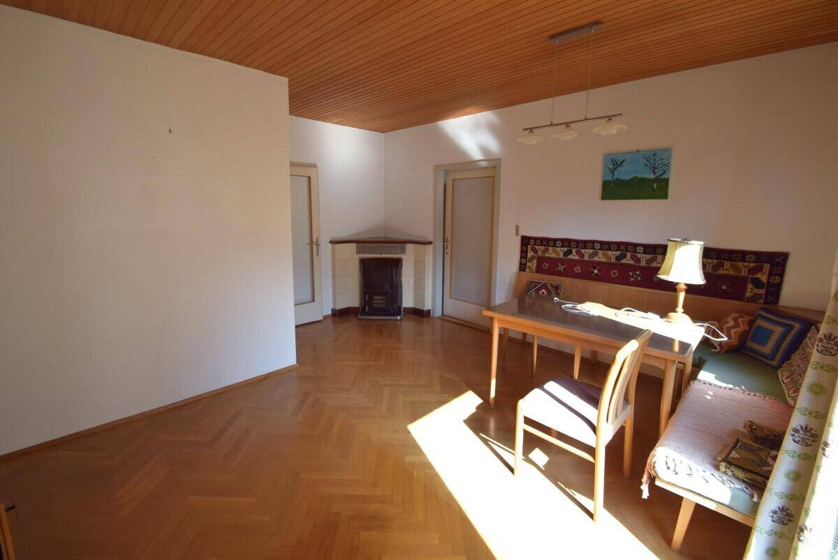 Wohnzimmer mit Parkettboden, Holzdecke und einem Kaminofen in der Ecke.