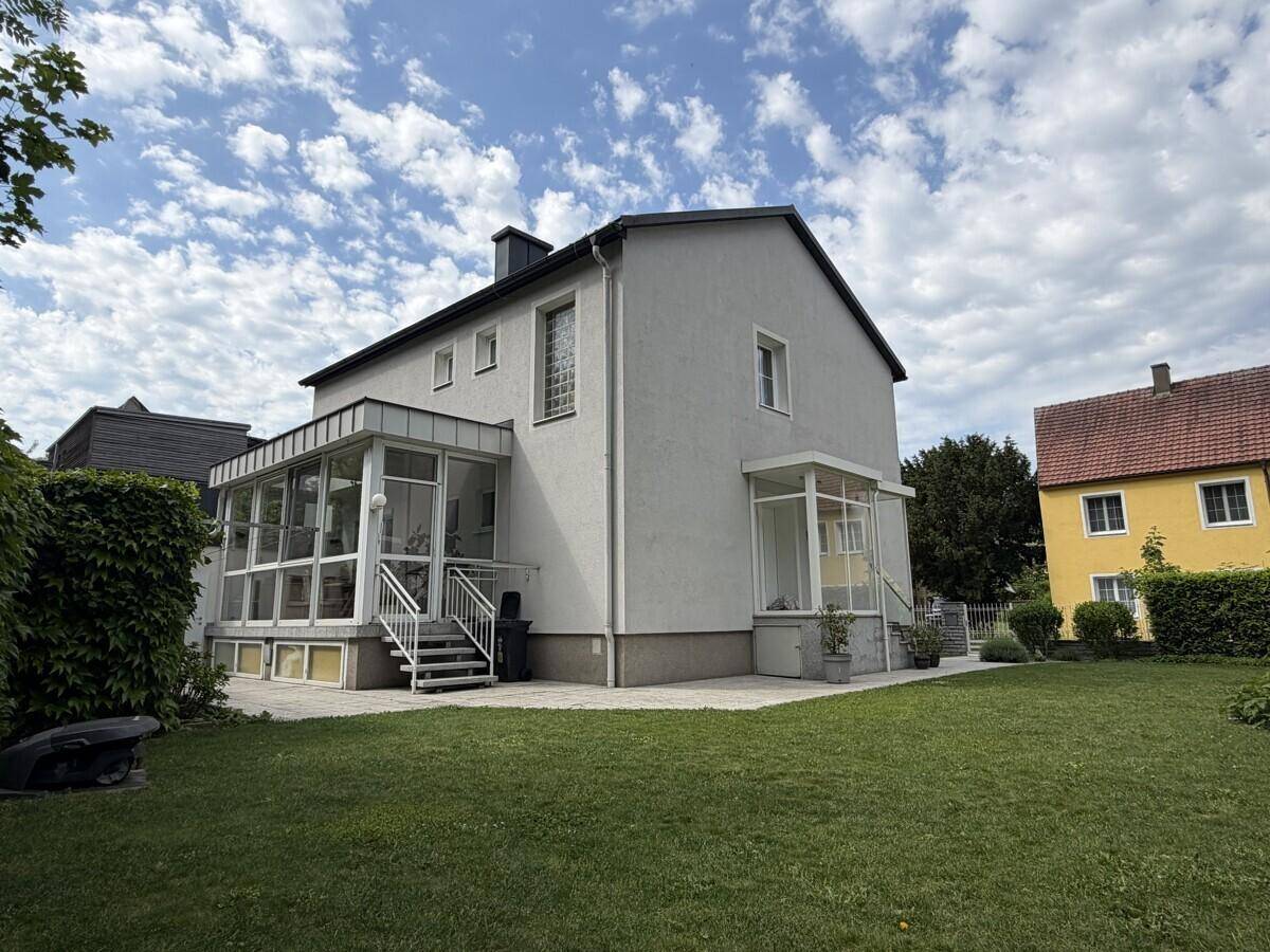 Rückseite des Hauses mit großem Garten, Rasenfläche und verglastem Wintergarten.