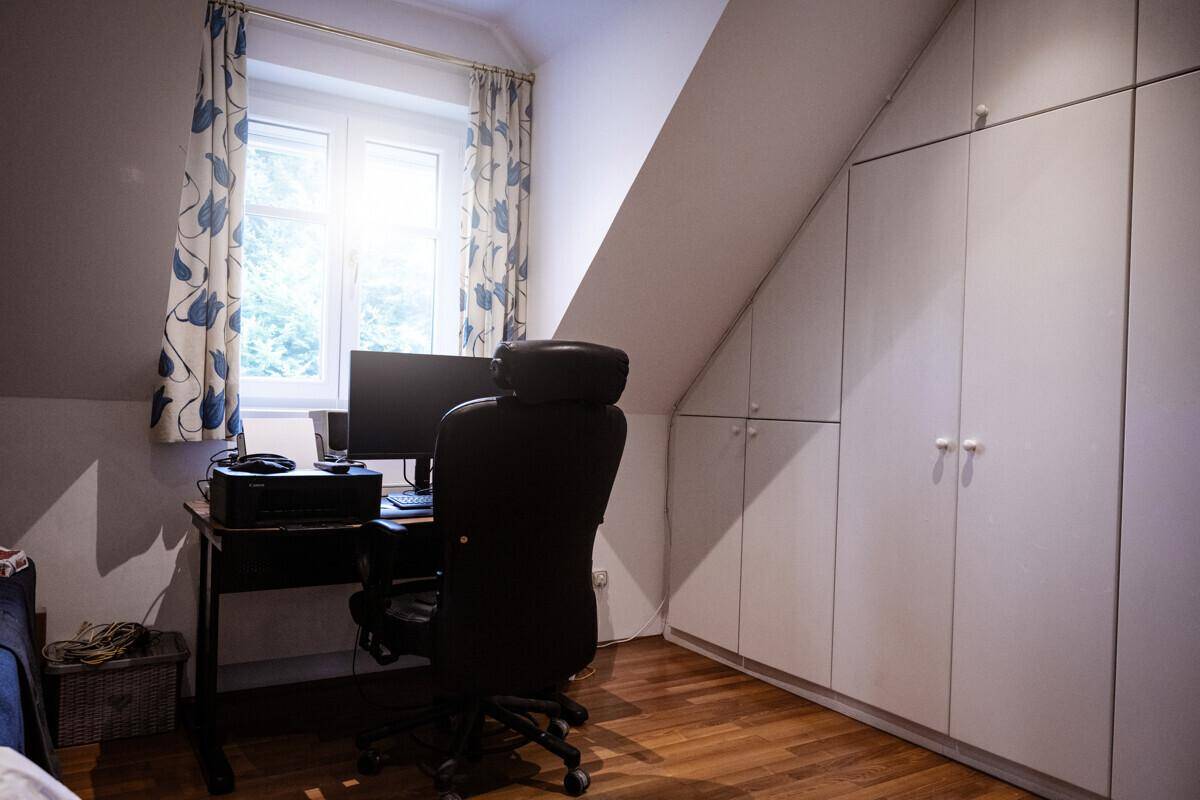 Arbeitszimmer im Dachgeschoss mit Schreibtisch, Einbauschränken und Fenster für natürliches Licht.
