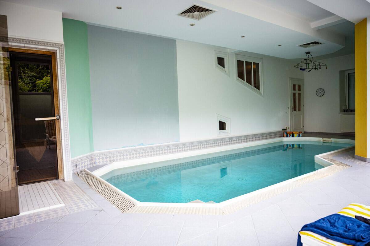 Geräumiges Hallenbad mit Fliesenboden und Zugang zum Außenbereich, ideal für Sport und Entspannung.