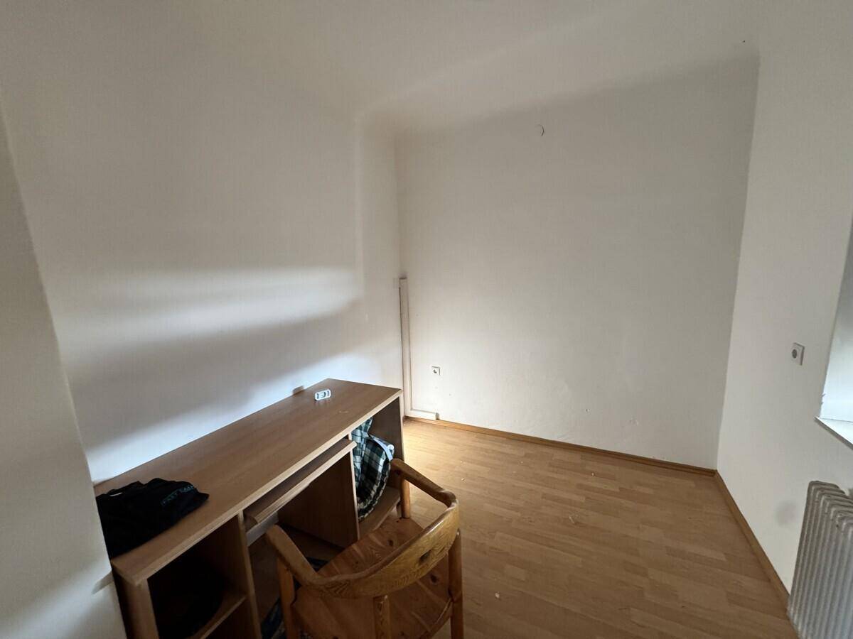Kleiner Raum mit Holzboden und einfacher Einrichtung, ideal als Büro oder Gästezimmer.