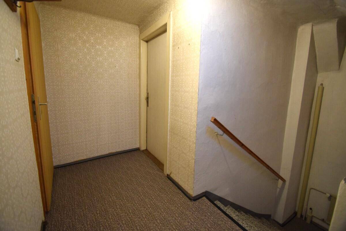 Kellerflur mit Teppichboden und Zugang zu weiteren Kellerräumen.