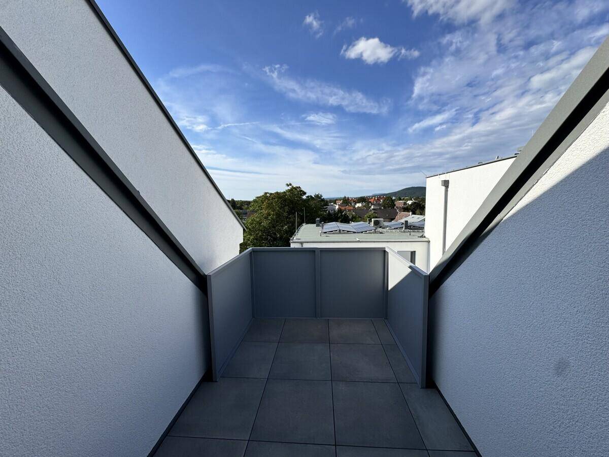 Kleiner, überdachter Außenbereich mit Fliesenboden und Blick auf die Umgebung.