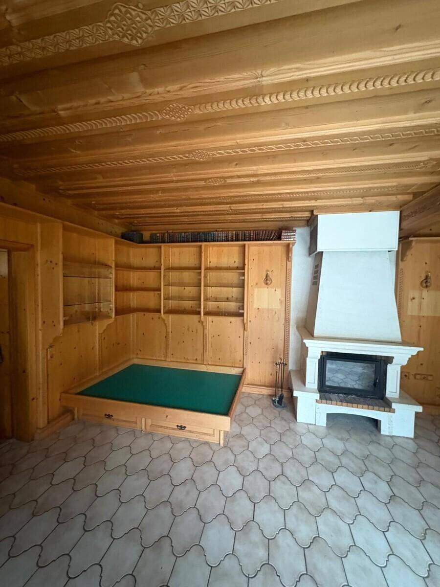 Rustikaler Wohnraum mit Holzwänden, Kamin und gemustertem Fliesenboden.