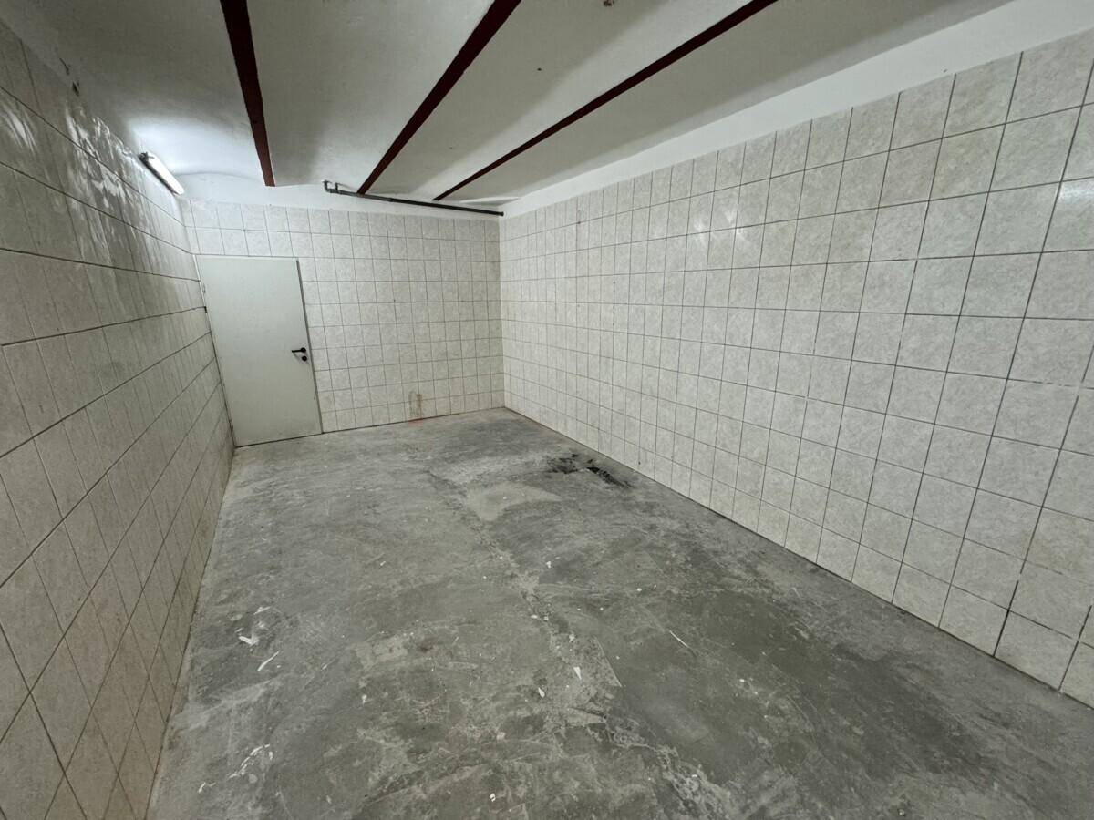Praktischer Abstellraum mit gefliesten Wänden und Betonboden, ideal für Lagerzwecke.
