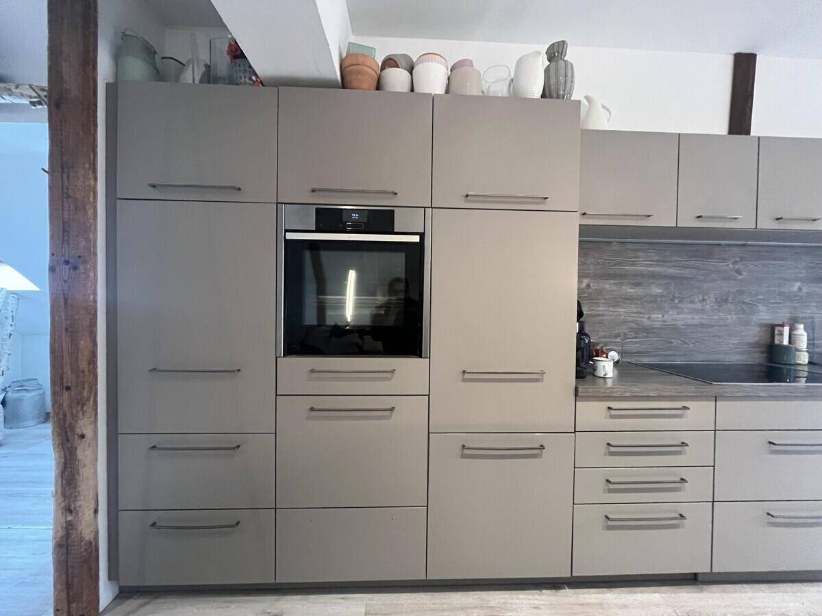 Einbauküche mit modernen grauen Schränken und integriertem Backofen.
