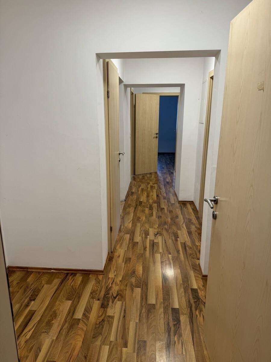 Langer Flur mit Laminatboden und mehreren Türen, der die Zimmer miteinander verbindet.