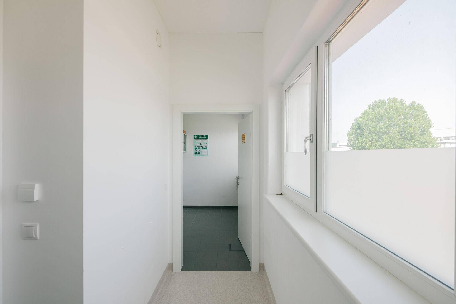 Schmaler, heller Flur mit Fenster und Zugang zu weiteren Räumen, gut beleuchtet und funktional.