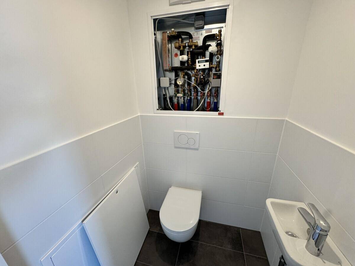 Gäste-WC mit wandhängender Toilette, kleinem Waschbecken und Technikschacht.