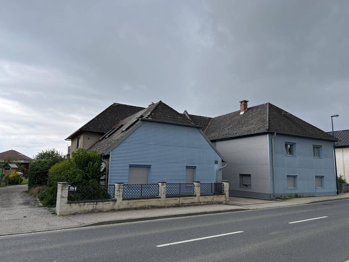Ansicht des Wohnhauses von der Straße mit blauer Fassade und Satteldach.
