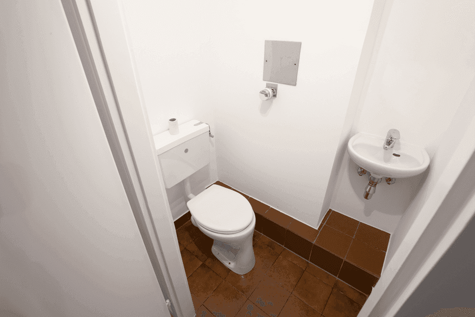Separate Gästetoilette mit WC, kleinem Waschbecken und Terrakotta-Fliesenboden.