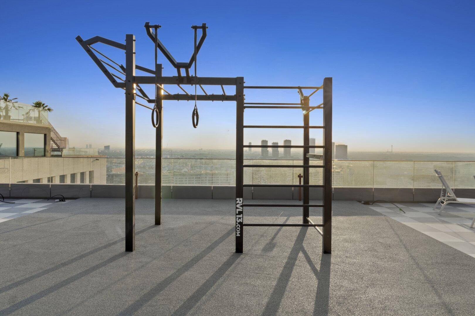 Outdoor-Fitnessbereich auf einer Dachterrasse mit Klettergerüst und Panoramablick über die Stadt.