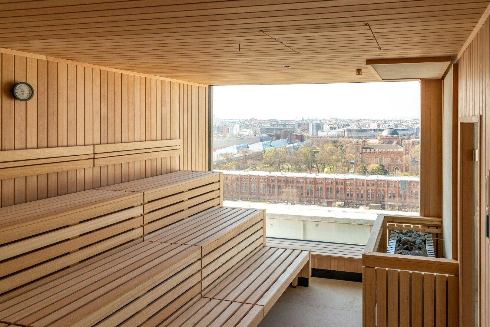Moderne Sauna mit Holzverkleidung und großem Fenster mit Blick auf die Stadt.