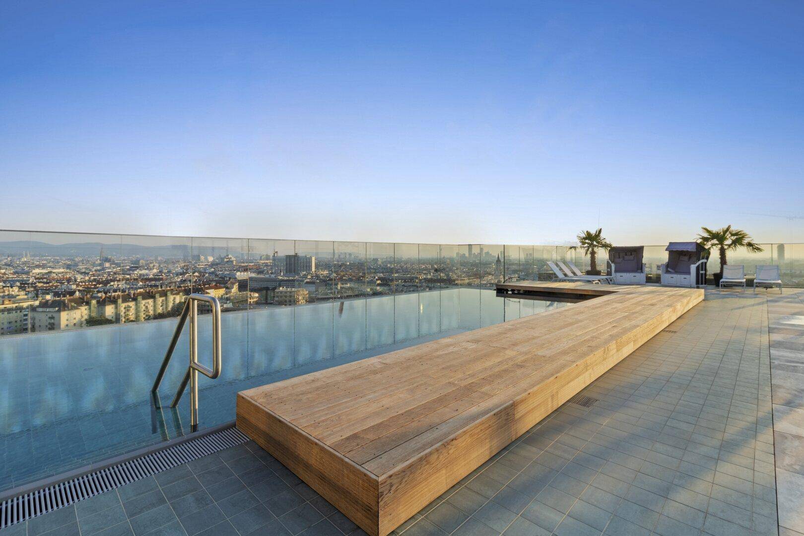Infinity-Pool auf dem Dach mit Holzdeck und atemberaubendem Stadtpanorama unter blauem Himmel.