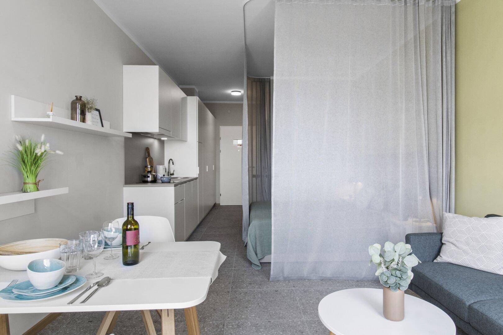 Offenes Studio-Apartment mit Essbereich, Küchenzeile und abgetrenntem Schlafbereich.