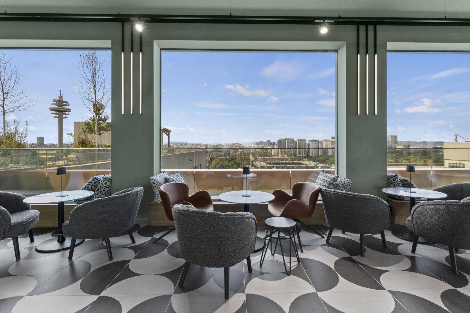 Komfortabler Lounge-Bereich mit Panoramablick auf die Stadt und moderne Einrichtung.