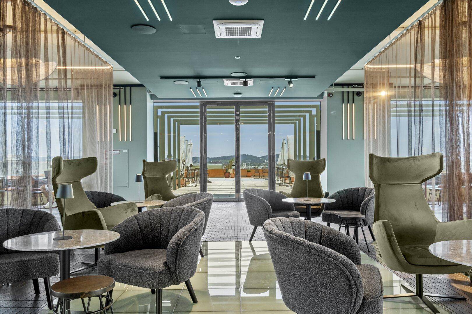 Geräumiger Lounge-Bereich mit stilvollen Sitzgelegenheiten und Zugang zur Dachterrasse.