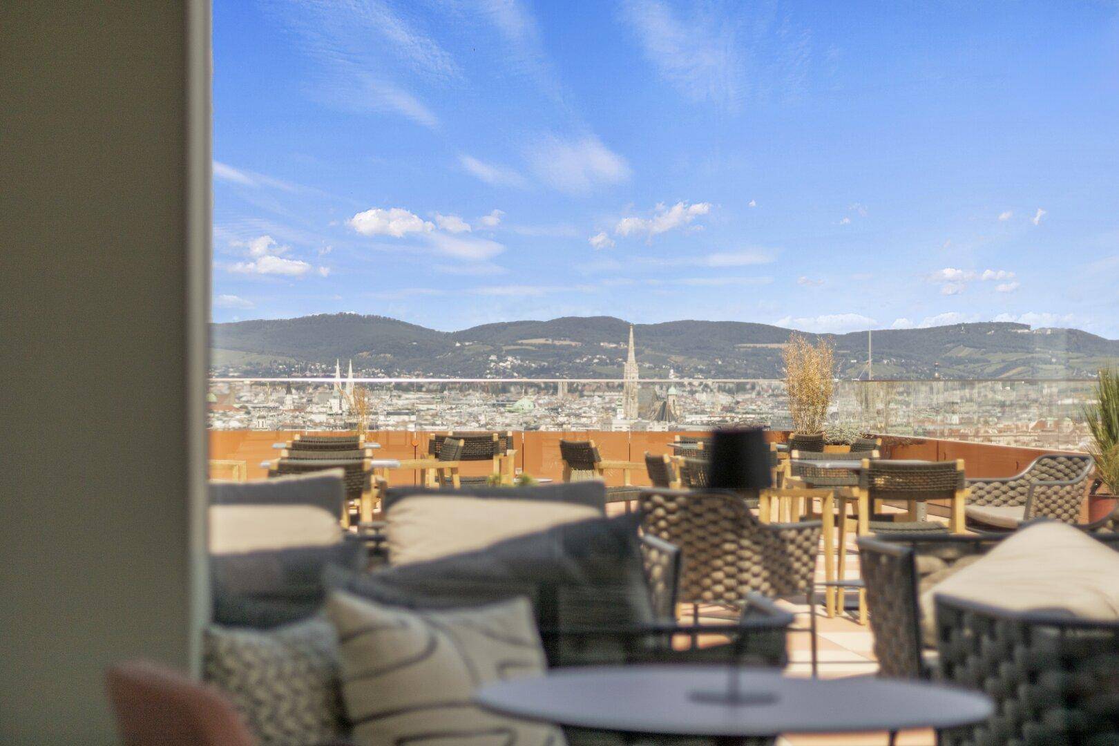 Weitläufige Dachterrasse mit bequemen Sitzgegelegenheiten und beeindruckendem Stadt- und Bergblick.