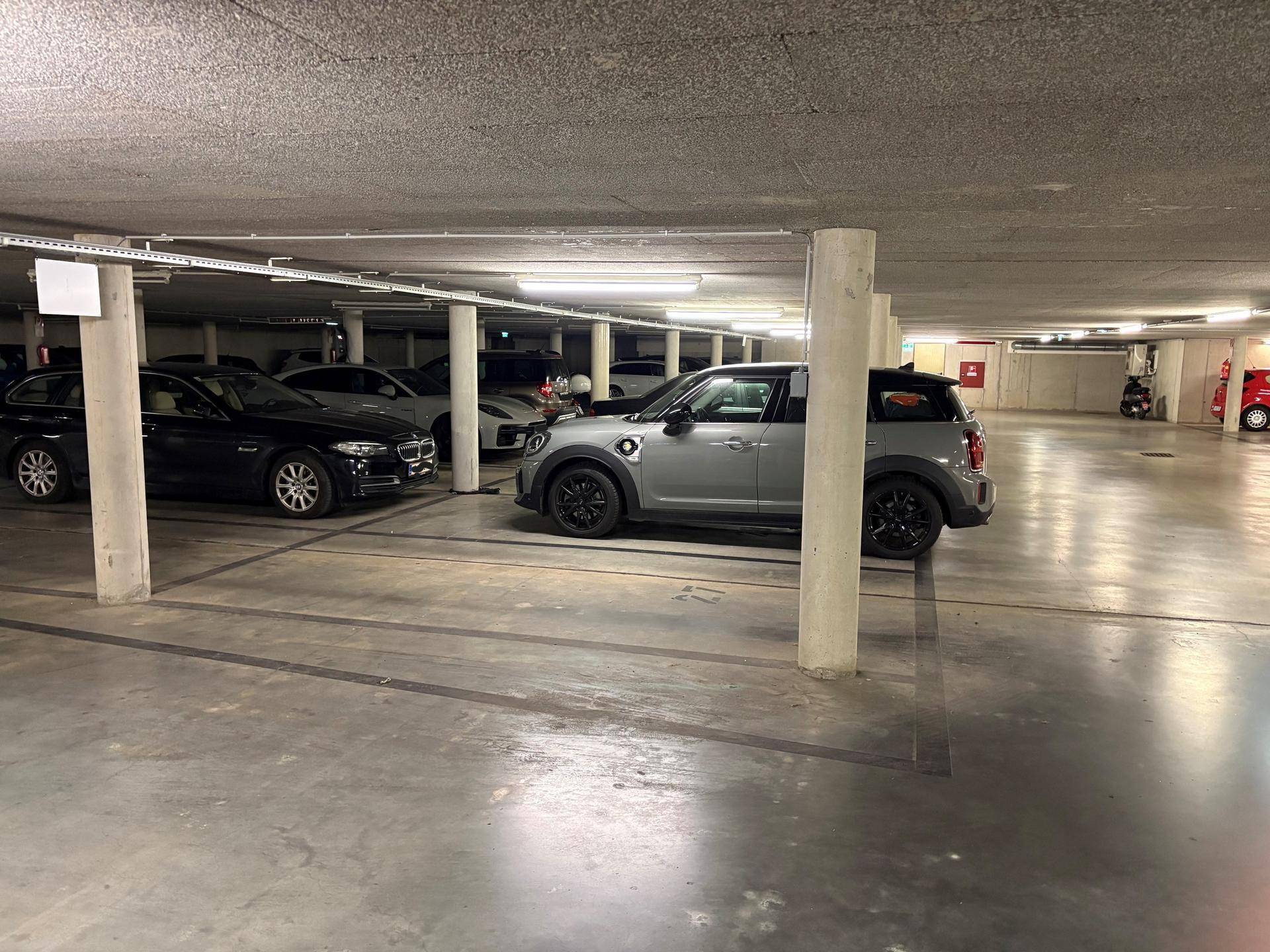 Moderne Tiefgarage mit sauberem Betonboden und vielen geparkten Fahrzeugen.