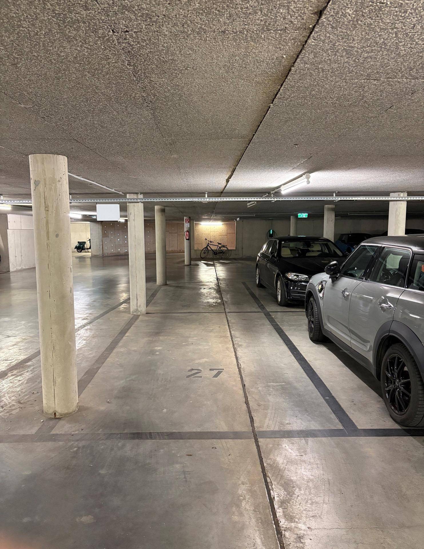 Übersichtliche Tiefgarage mit nummerierten Stellplätzen und robusten Betonwänden.