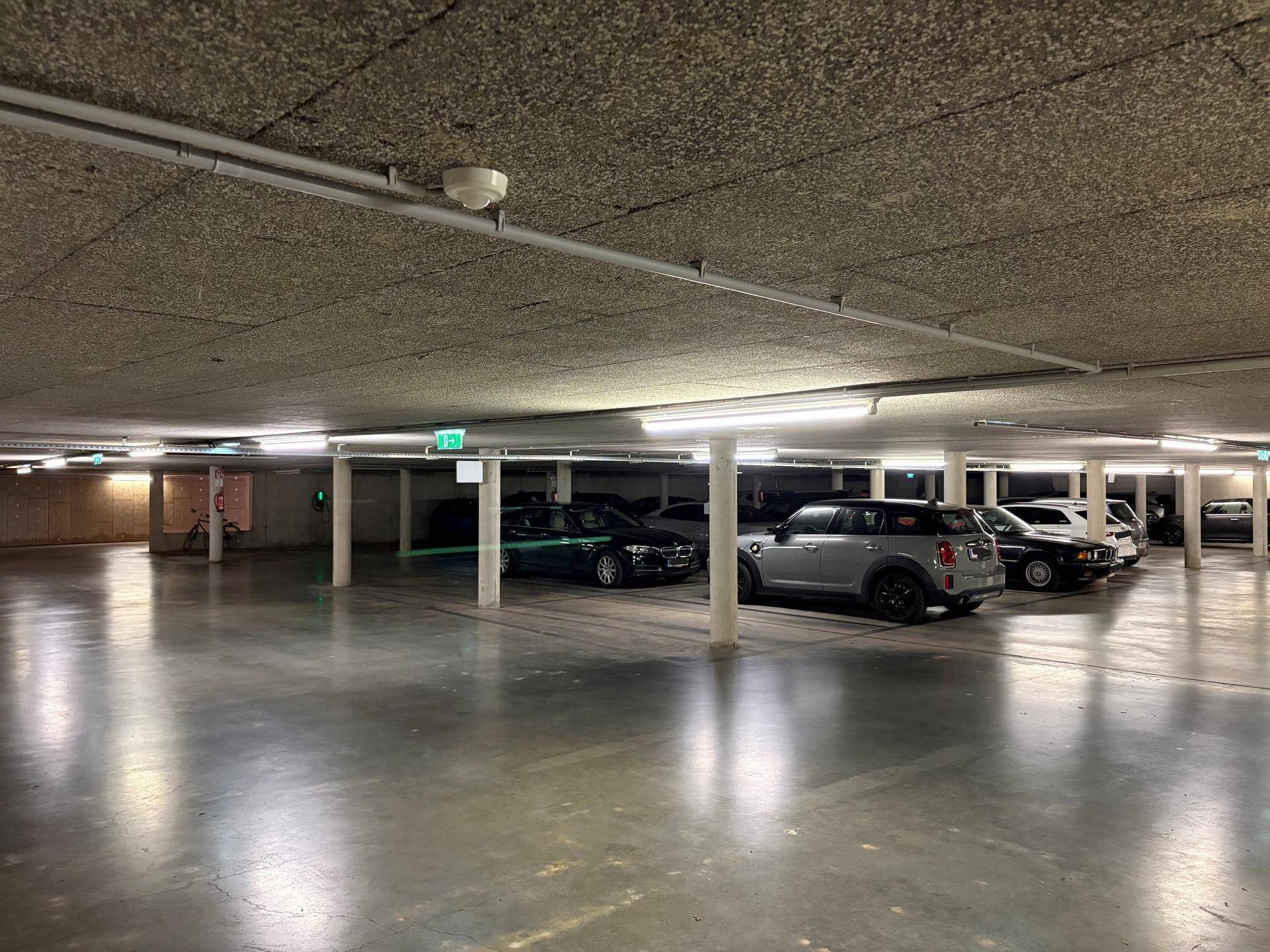 Helle und saubere Tiefgarage mit vielen Parkplätzen und guter künstlicher Beleuchtung.