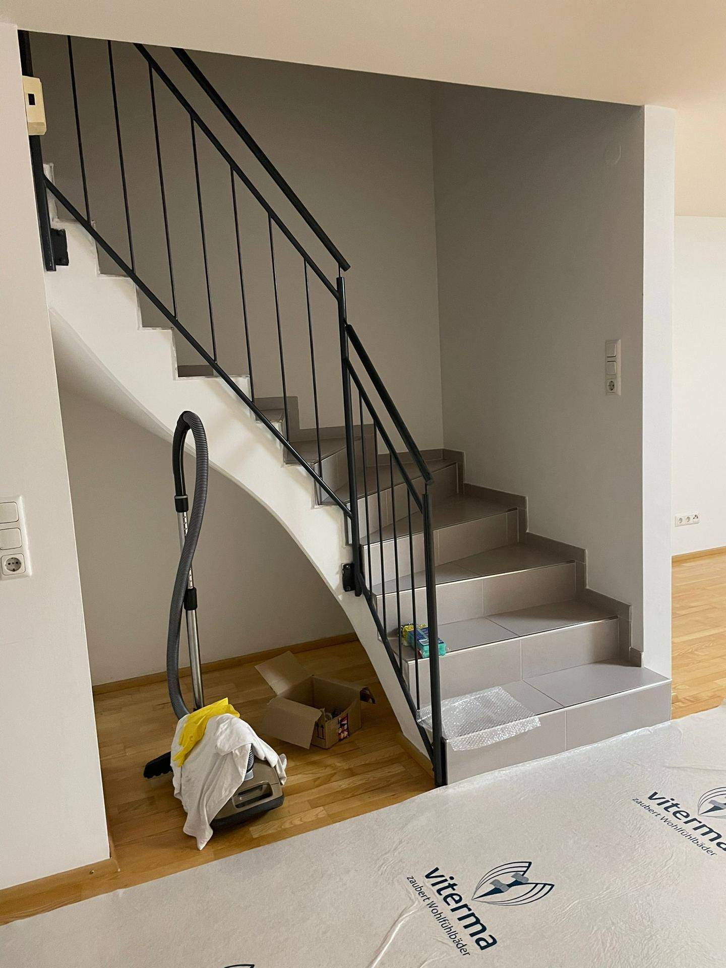 Treppenhaus mit modernem Geländer und Fliesenstufen, führt in die obere Etage.