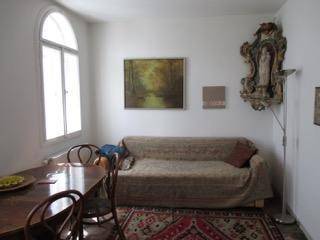 Heller Wohn-Essbereich mit Sofa, Esstisch und einem großen Bogenfenster.