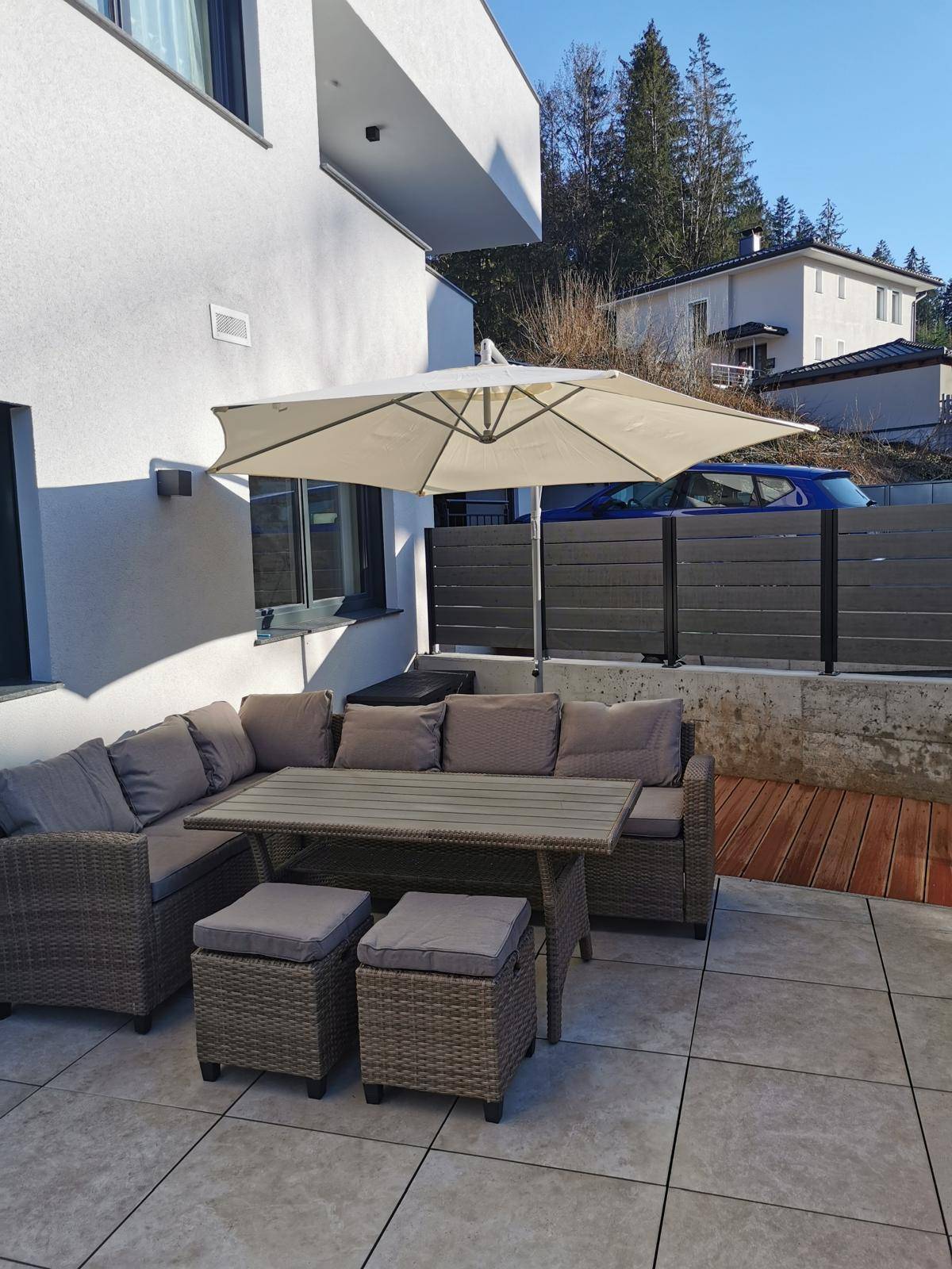 Sonniger Terrassenbereich mit bequemen Gartenmöbeln und großem Sonnenschirm.