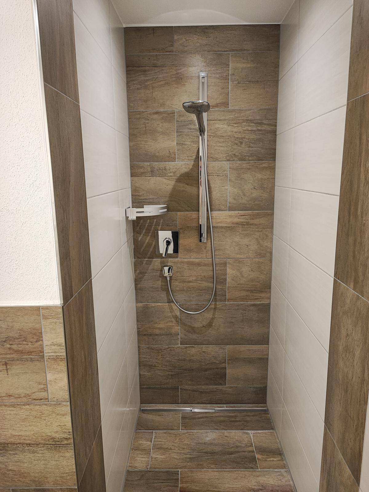 Moderne begehbare Dusche mit stilvollen braunen und weißen Fliesen.