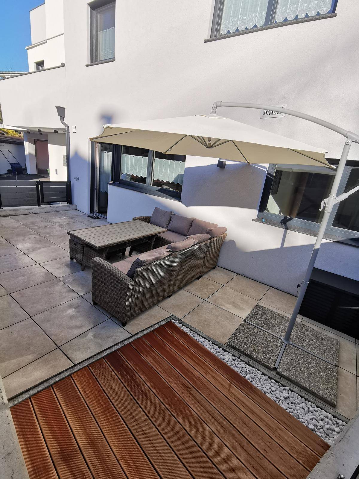 Weitläufige Terrasse mit Sitzgelegenheiten, Sonnenschirm und Holzdeck-Elementen.