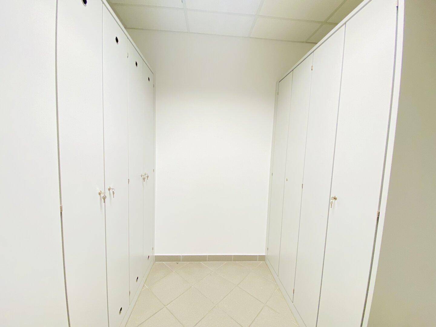 Raum mit weißen Spinden und Fliesenboden, ideal als Umkleide- oder Abstellraum für Mitarbeiter.