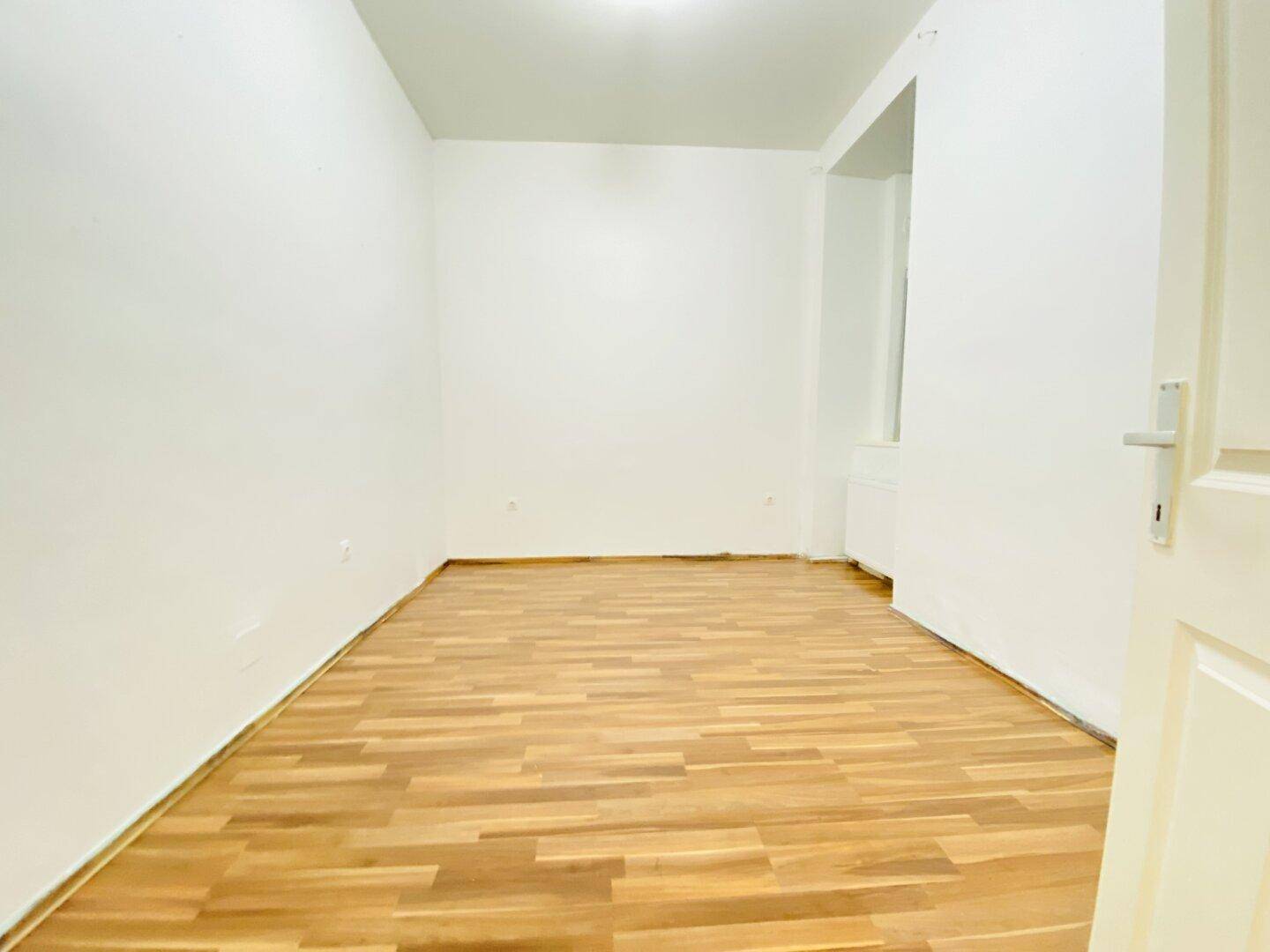 Geräumiges Zimmer mit Laminatboden und weißen Wänden, bietet vielseitige Nutzungsmöglichkeiten.