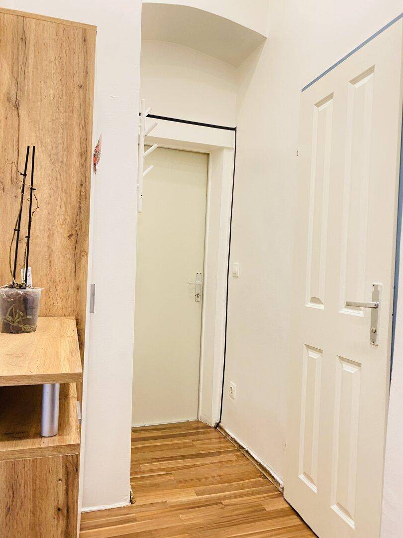 Eingangsbereich mit Laminatboden und einem praktischen Holzschrank, der zusätzlichen Stauraum bietet.
