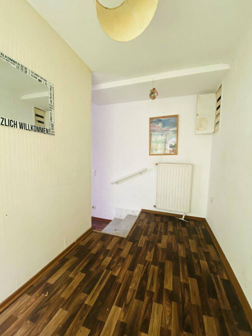 Eingangsbereich mit Laminatboden, Heizkörper und Treppe, die in den oberen Bereich des Hauses führt.