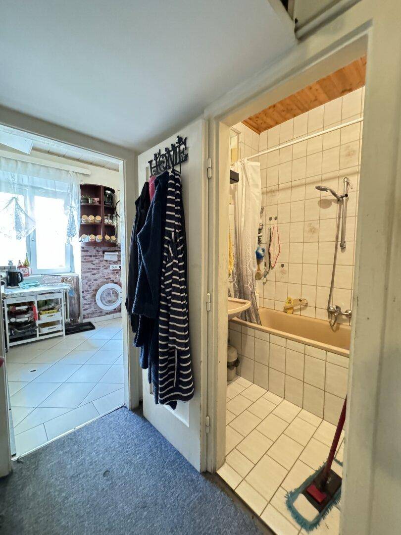 Blick vom Flur in ein Badezimmer und eine Küche mit Fliesenboden.