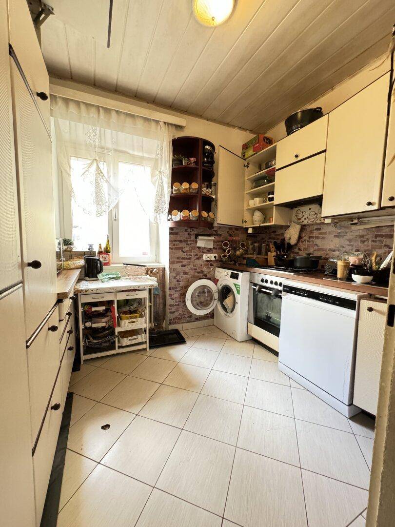 Funktionale Küche mit weißen Schränken, Fliesenboden und einem Fenster für Tageslicht.