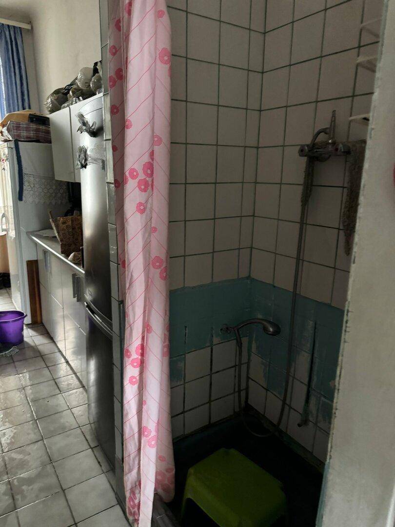 Einfaches Badezimmer mit Duschbereich, Fliesen und einem rosa Duschvorhang.