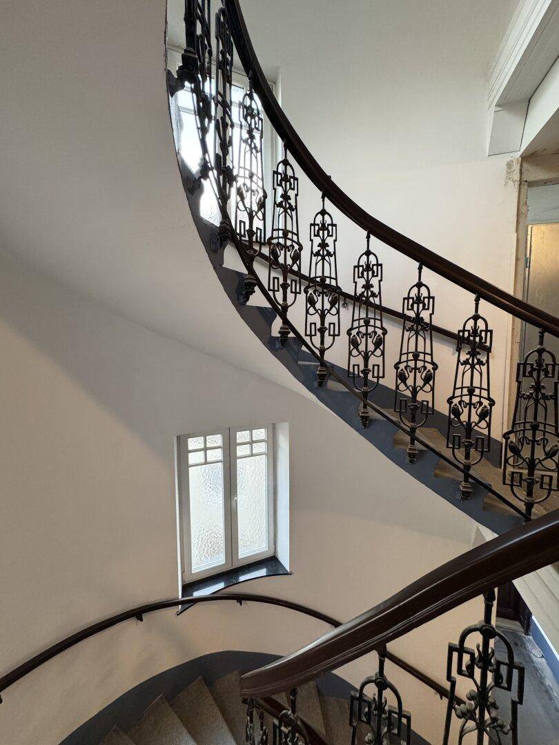Historisches Treppenhaus mit kunstvollem schmiedeeisernem Geländer und Holzhandlauf.