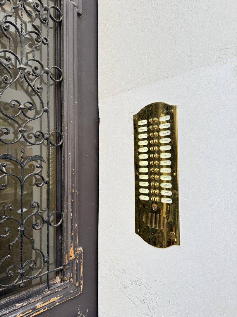 Detailansicht einer historischen Fassade mit vielen Fenstern und einem klassischen Klingeltableau.