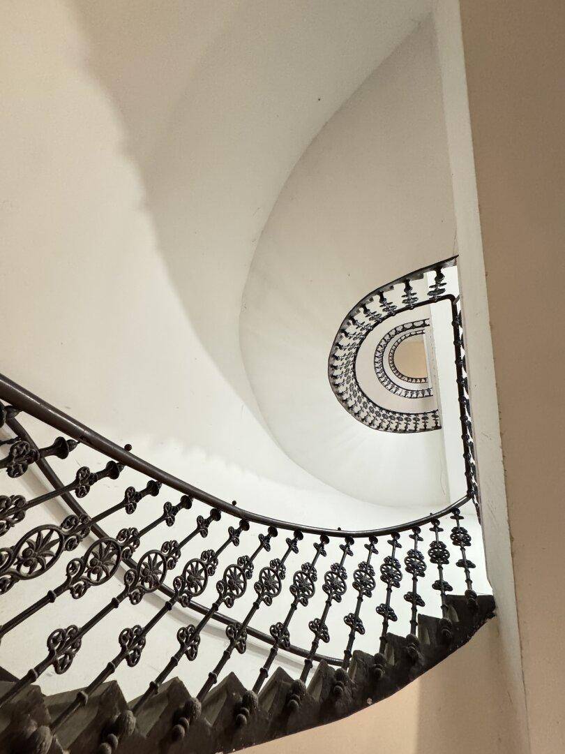 Historisches Treppenhaus mit kunstvollem schmiedeeisernem Geländer und Wendeltreppe.