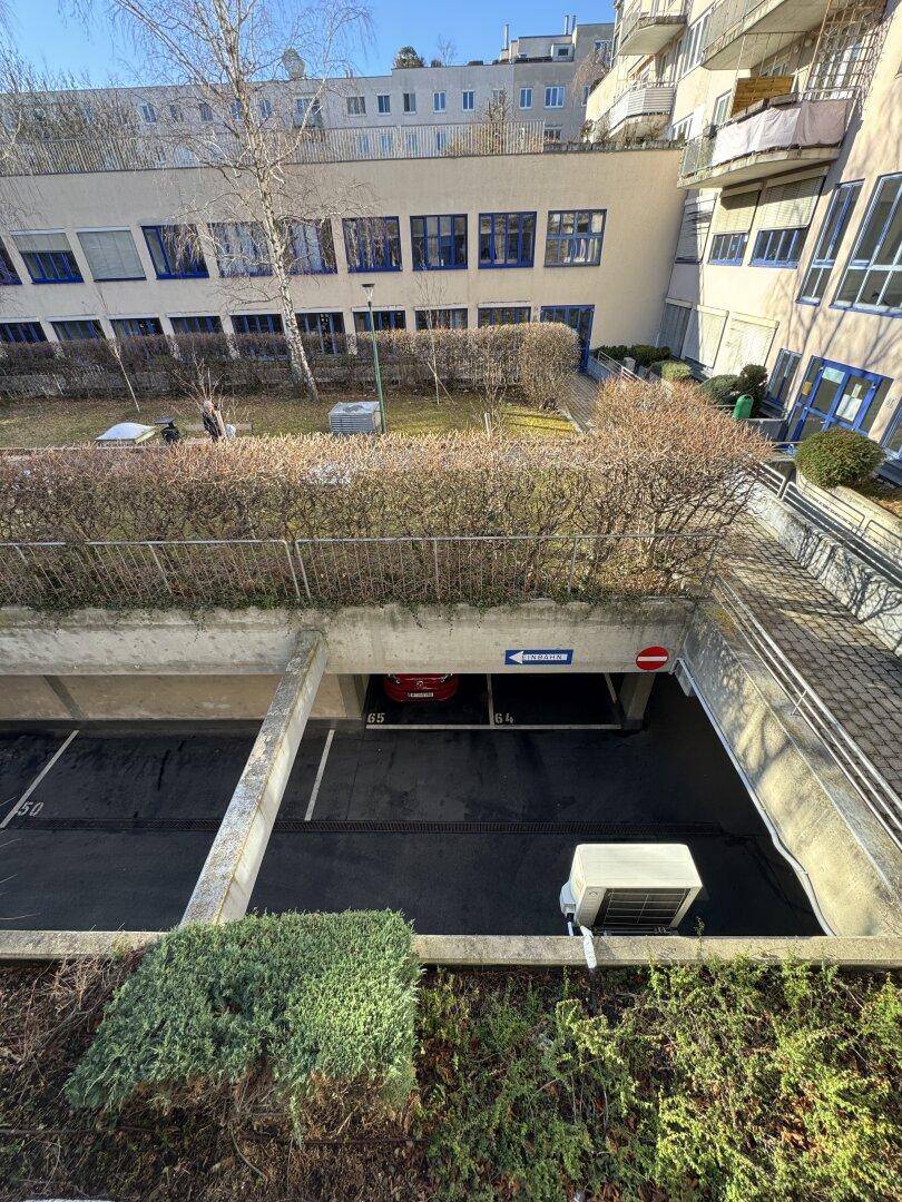 Eingang zur Tiefgarage mit Rampe und umliegender Grünfläche des Gebäudekomplexes.
