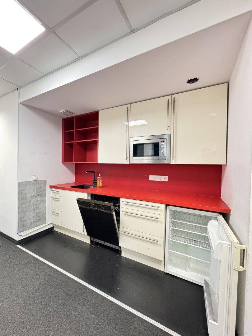 Kleine Küchenzeile mit weißen und roten Schränken, Spülmaschine, Mikrowelle und Kühlschrank.