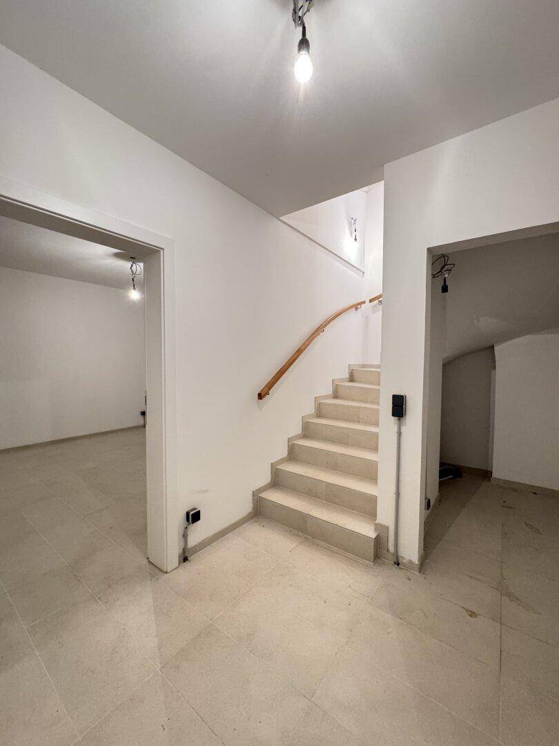Heller Flur mit einer Treppe, die in die oberen Stockwerke führt, und einem gefliesten Boden.